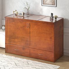 a wooden cabinet with two doors and drawers in a living room next to a white rug