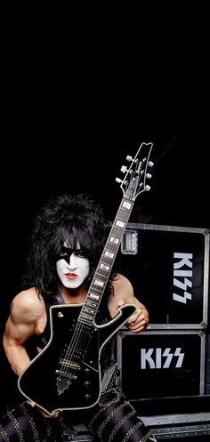 a man with white makeup holding a guitar