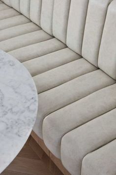 a white marble table sitting on top of a wooden floor next to a beige couch