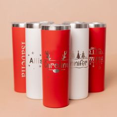 four red and white travel mugs sitting next to each other on a pink surface