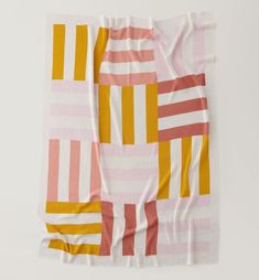 a pink, yellow and white striped blanket on top of a table next to a wall