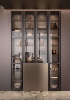 a metallic cabinet with glass doors and dishes on it's shelves in a kitchen