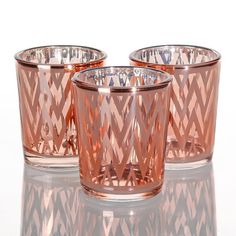 three pink glass candlesticks sitting next to each other