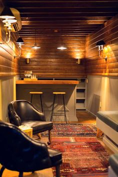 a living room filled with furniture next to a wooden wall and ceiling mounted light fixture