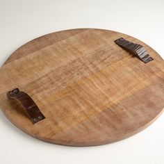 a wooden cutting board with a knife on it's side and some brown leather handles