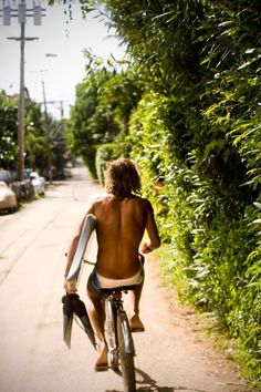 a shirtless man riding a bike down a street