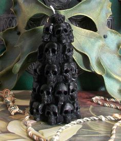 a black candle with skulls on it sitting next to a green plant