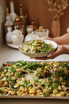 a person holding a plate of food on top of a pan