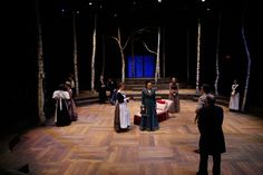 a group of people standing on top of a wooden floor in front of a stage