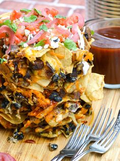 a stack of food sitting on top of a wooden cutting board next to a fork