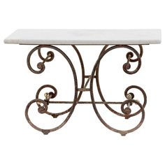 a white marble top table with wrought iron frame and scroll work on the base, against a white background