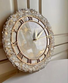 a clock that is sitting on the side of a wall with pearls around it and roman numerals