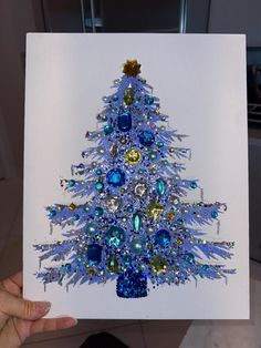 a hand holding up a card with a blue christmas tree on it