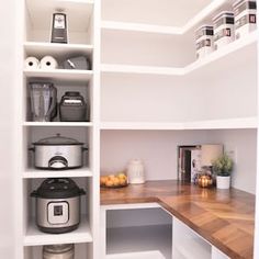 an organized pantry with white shelving and wooden counter tops