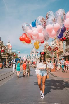 a woman is walking down the street with balloons