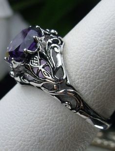 Natural Amethyst Ring Daisy Design#66 In Stock Size 6 Inspired by the Art Nouveau movement of the early 20th century, I now offer this lovely reproduction filigree ring in sterling silver. This gorgeous ring is set with a genuine/natural 1.5ct purple amethyst gemstone; which has a great shine and very good clarity. The round full cut purple amethyst gemstone is 8mm (5/16th of an inch) in diameter. The ring measures 12mm NS on the finger. The inside of the band is marked 925 for sterling. Notice Purple Intricate Design Promise Ring, Purple Promise Ring With Intricate Design, Purple Amethyst Ring With Intricate Design For Promise, Purple Amethyst Promise Ring With Intricate Design, Ornate Amethyst Purple Ring, Ornate Purple Amethyst Ring, Ornate Purple Ring For Anniversary, Intricate Design Purple Amethyst Ring, Purple Amethyst Rings With Intricate Design