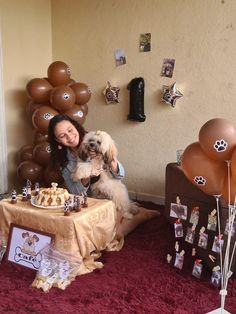 a woman sitting on the floor with her dog next to a table full of desserts and balloons