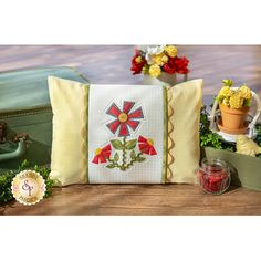 a pillow sitting on top of a wooden table next to flowers and potted plants