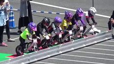 several children are riding their bikes on the track