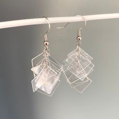 two clear square shaped earrings hanging from a white string