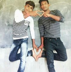 two young men standing next to each other with their hands in the shape of a heart