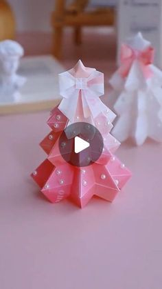 an origami christmas tree with pink and white bows on it's head