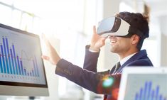 a man wearing a virtual reality headset in front of a computer screen with graphs on it