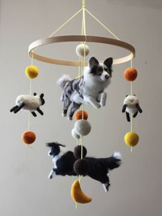 a dog is hanging from a mobile made out of wool