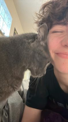 a person that is kissing a cat on the nose