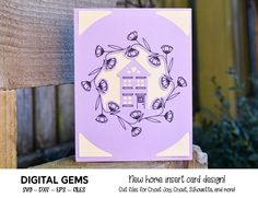 a purple card with a house in the center and flowers around it on a wooden fence