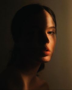 a woman's face is lit by a light from a lamp on the wall