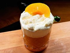 there is a drink with whipped cream and an orange garnish