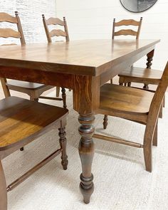 a wooden table with chairs around it and a round mirror on the wall behind it