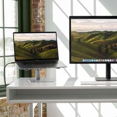 two computer monitors sitting on top of a white desk