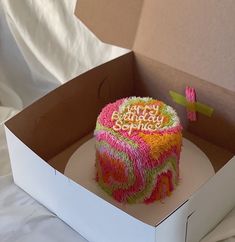 a birthday cake in a box on a bed