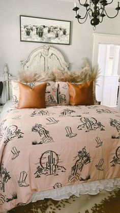 a bed with pink and brown comforters in a bedroom next to a chandelier