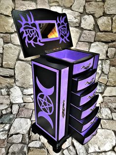 a purple and black dresser sitting on top of a stone floor