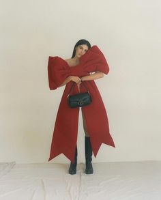 a woman in a red coat holding a black purse