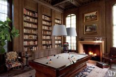 a pool table in the middle of a living room with lots of bookshelves