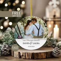 a christmas ornament with a couple kissing in front of a tree and pine cones