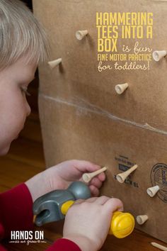 a young boy playing with wooden pegs in front of a cardboard box that says hammering tees into a fine motor practice for toddlers