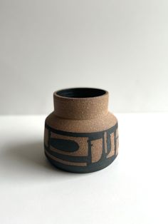 a black and brown vase sitting on top of a white table