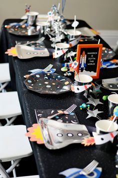 a black table topped with lots of plates and silverware covered in confetti