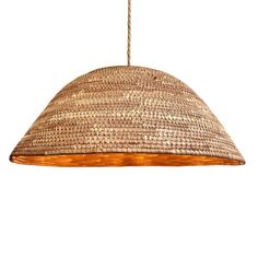 a light that is hanging from a rope on a white wall and has a woven shade over it