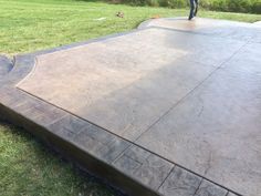 a man standing on top of a cement slab in the grass next to a park