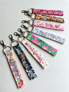 six keychains with different designs on them are lined up in the same row