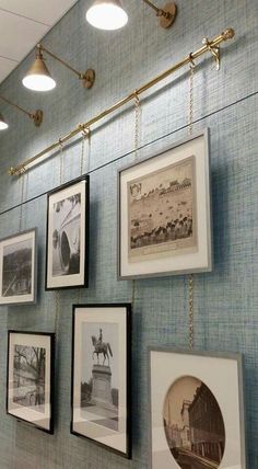 a wall with pictures hanging on it and some lights above the photo frames in front of them