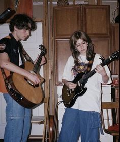 two young people are playing guitars in the kitchen