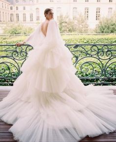 a woman in a wedding dress standing on a balcony with her back to the camera