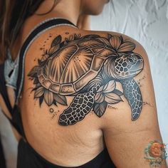 a woman's shoulder with a turtle and flowers tattoo design on it, in black and white